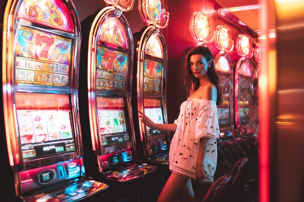 GOOD111 Slots — Thousands of exciting themes and jackpots A stylish woman beside vibrant slot machines displaying glowing sevens, showcasing the variety of top slots at GOOD111.